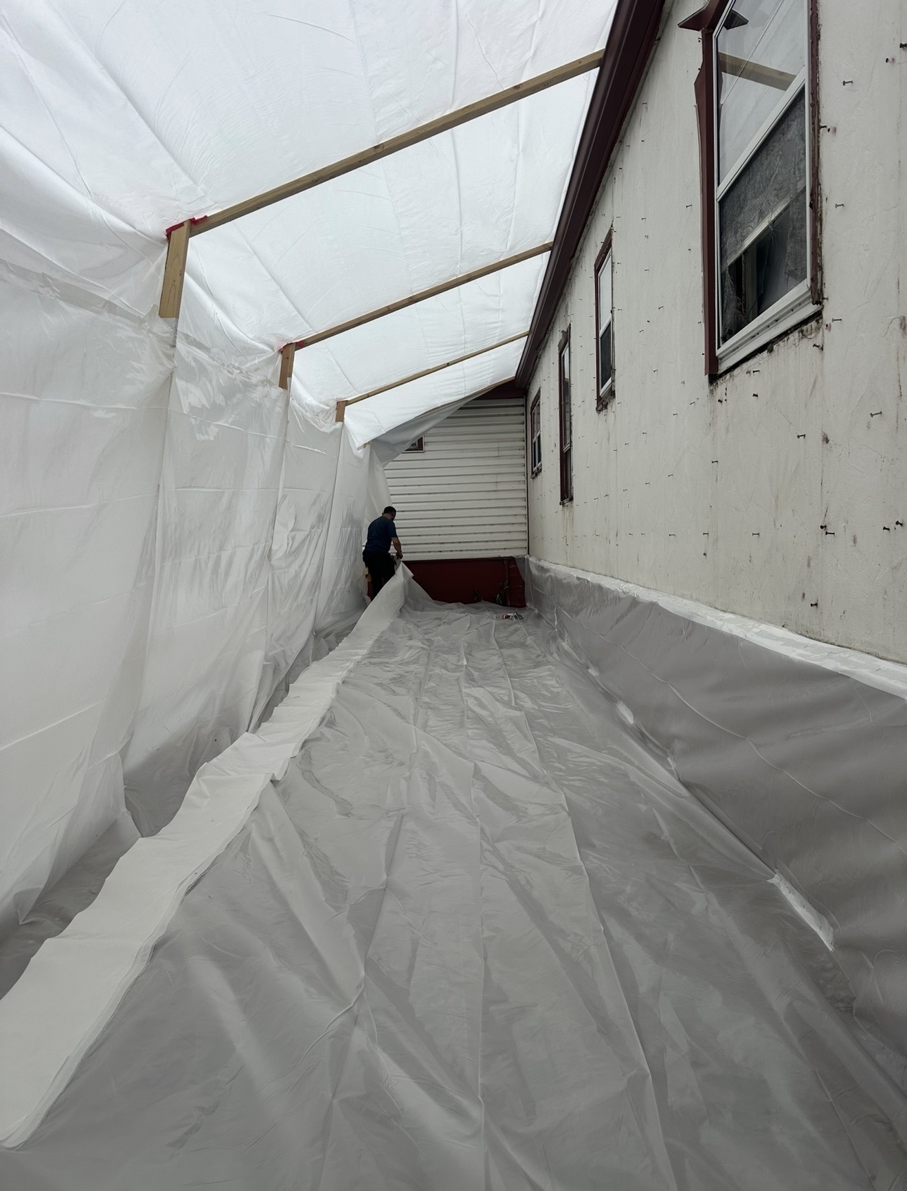 Exterior poly containment tunnel built along the side of a mobile home prior to asbestos siding removal
