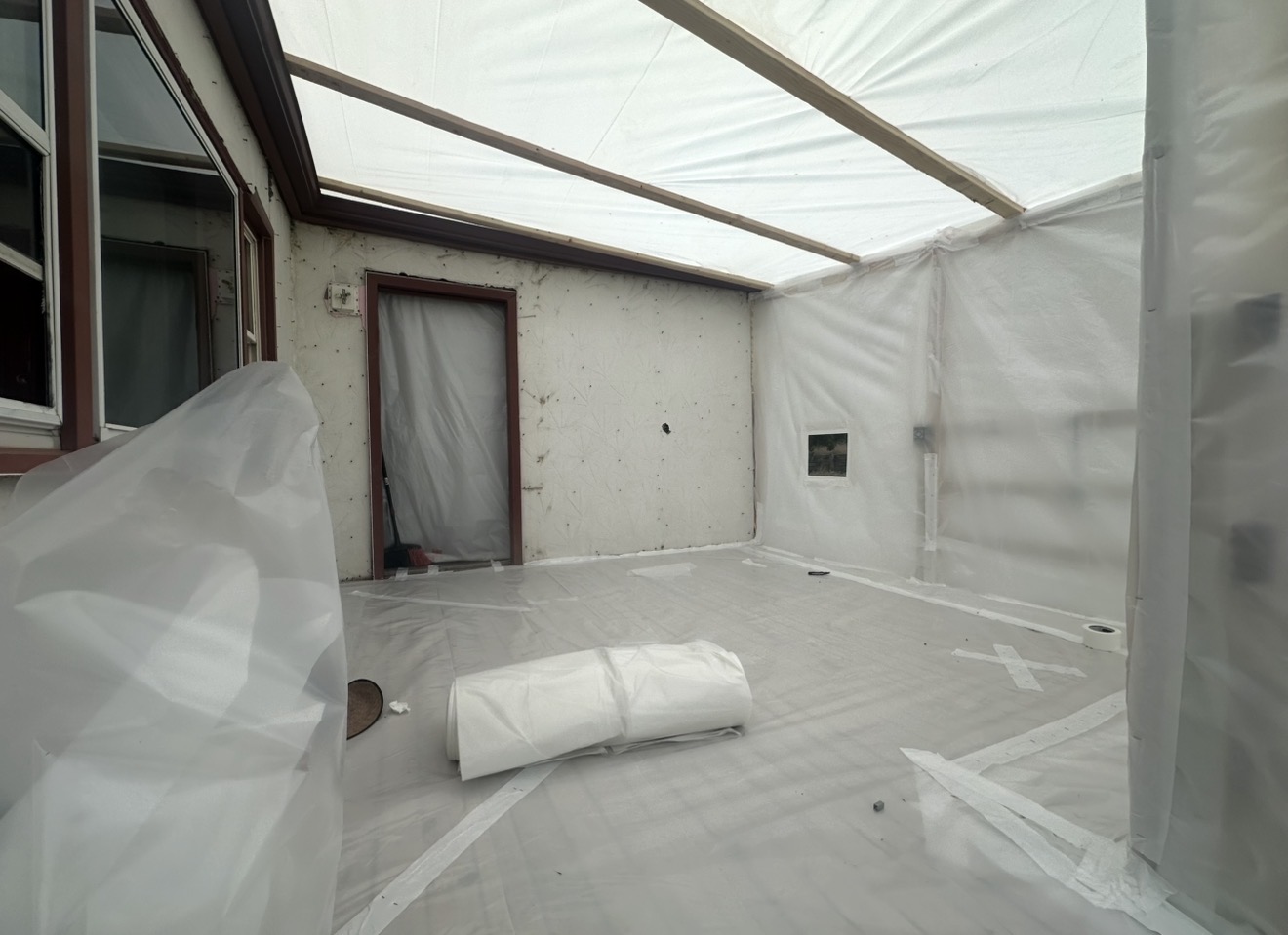 Interior room fully wrapped in poly sheeting with sealed doorway during asbestos containment