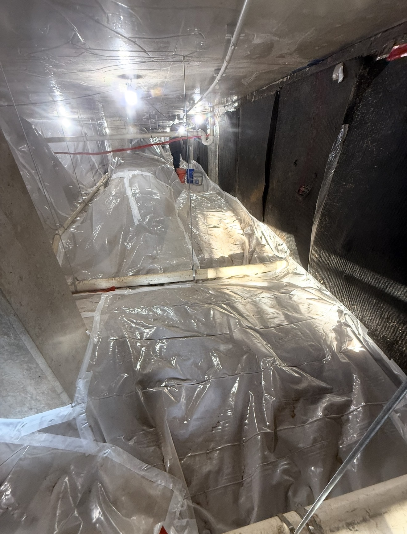Long interior corridor fully lined floor-to-ceiling with poly sheeting during multi-unit abatement