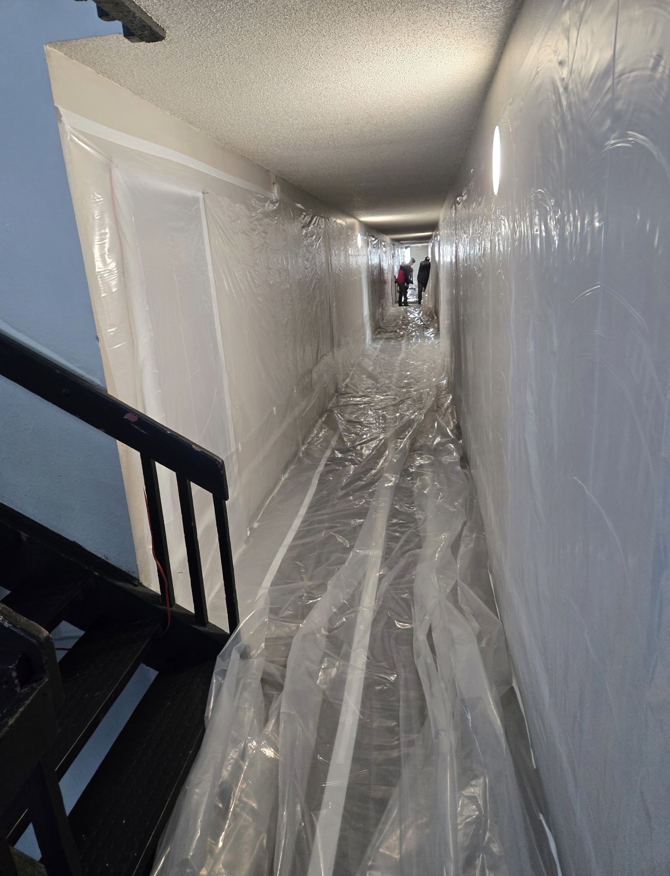 Exterior breezeway and stair landing of an apartment building wrapped in poly during asbestos work