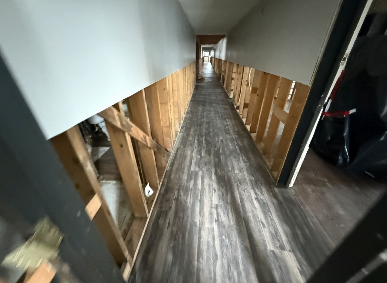 Open multi-room interior stripped to studs after asbestos drywall and flooring abatement, ready for clearance