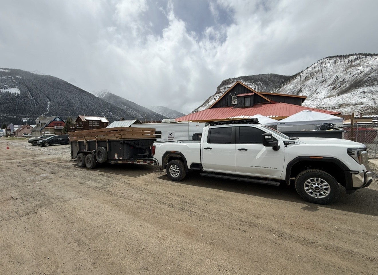 I&F Abatement Experts white GMC Sierra HD with dump trailer staged in a snowy Colorado mountain town