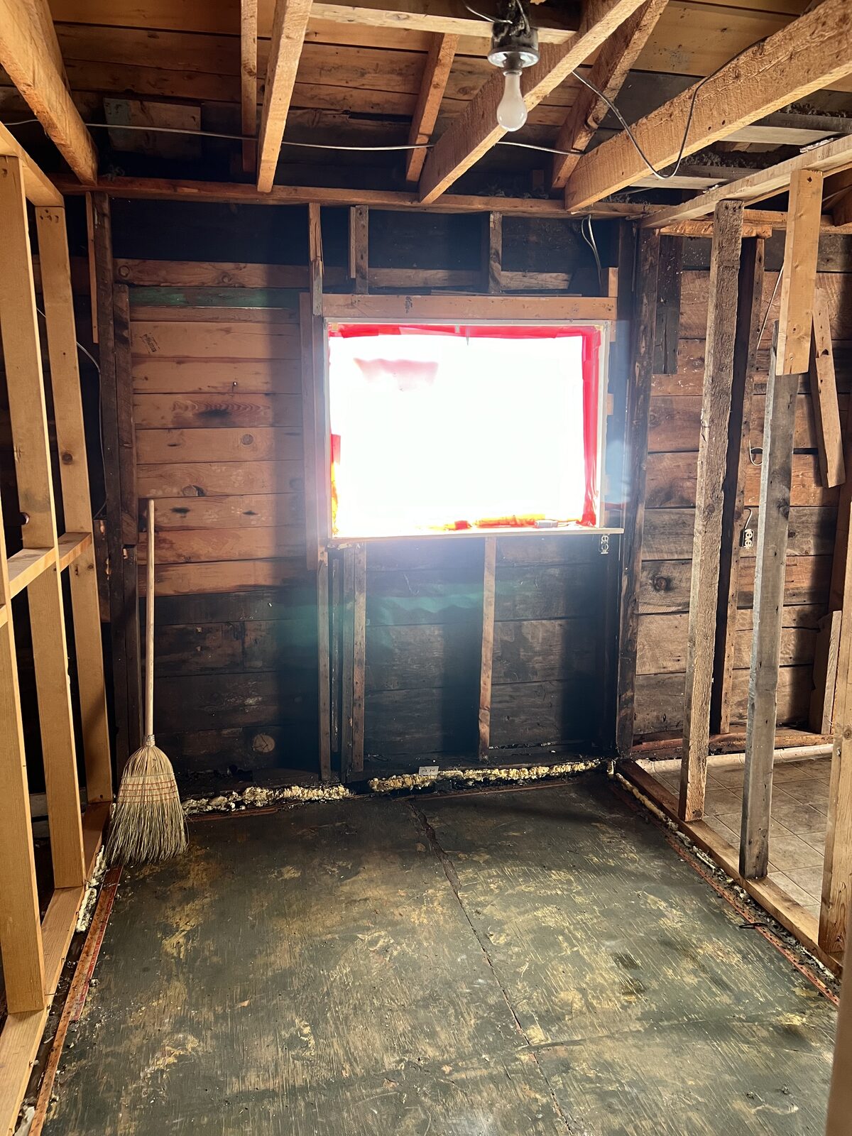 Demolition tools staged in a freshly abated room with original wood walls exposed