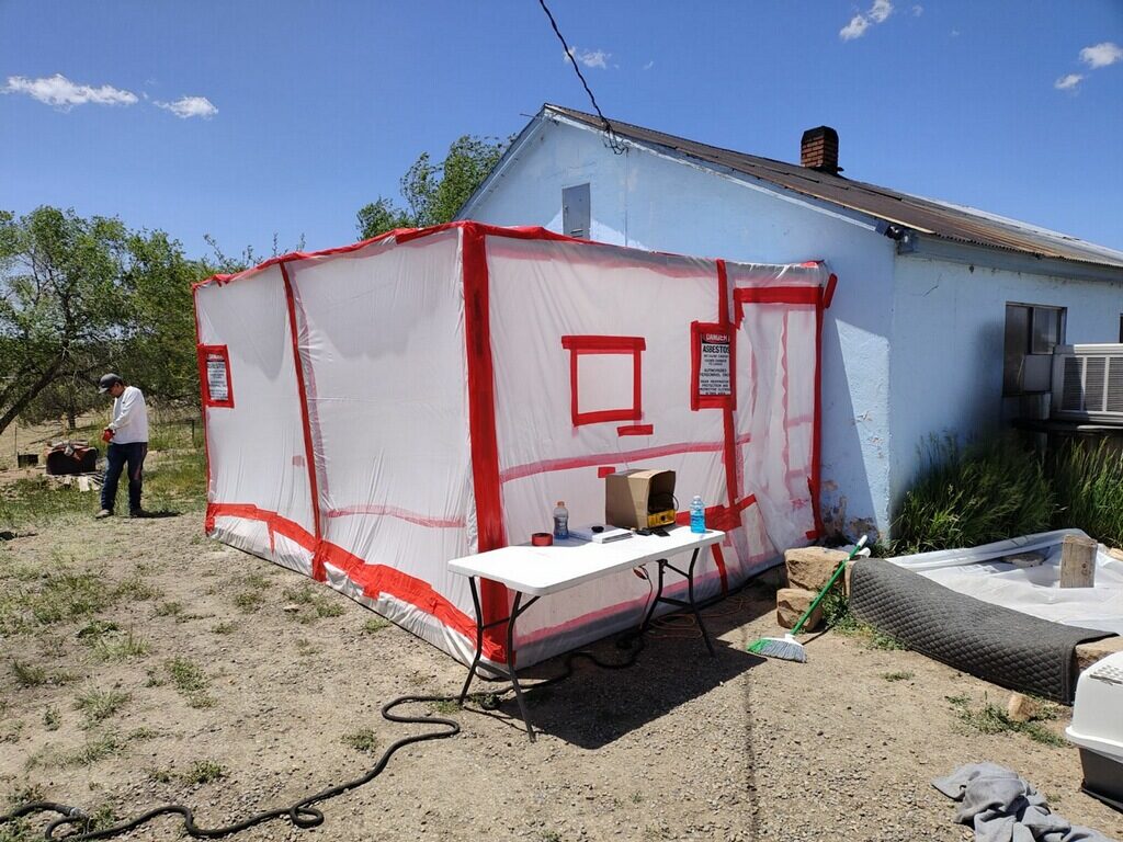 Engineered poly containment with decontamination chamber set up outside a single-story rural home